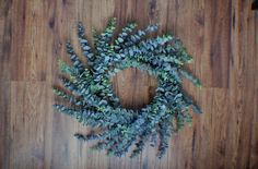 a wreath made out of green leaves on a wooden floor