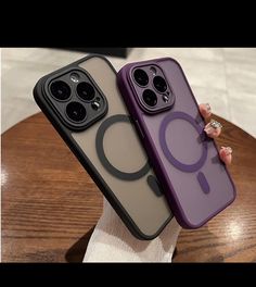 two cell phones are sitting next to each other on a wooden table, one is purple and the other is black