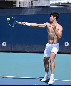 a shirtless tennis player swinging his racket at the ball