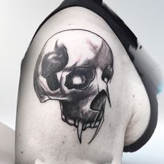 a black and white skull tattoo on the back of a man's shoulder,