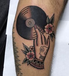 a person with a tattoo on their arm holding a record and flowers in front of them