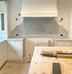 an unfinished kitchen with white cabinets and marble backsplash in the backround