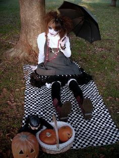 a woman sitting on top of a black and white checkered blanket next to a tree