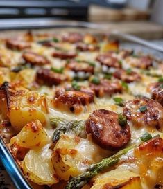 a casserole dish with sausage, potatoes and asparagus on it is ready to be eaten