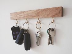 three keys hanging from a wooden hook on a wall with keychains attached to it