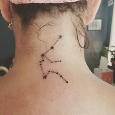 the back of a woman's neck has a small star tattoo on it