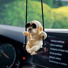 a small dog wearing sunglasses hanging from a car dashboard