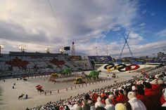 a large group of people standing in front of an olympic ceremony on the beach with horses