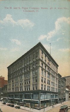 an old postcard shows the corner of a street in front of a large building