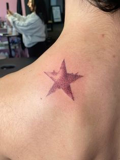 a woman with a star tattoo on her upper back shoulder and neck, looking at the camera