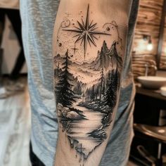 a man's arm with a compass tattoo on it and trees in the background