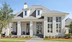 a white house with lots of windows and doors on the front porch, along with landscaping