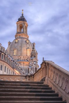 an old building with stairs leading up to it and a clock tower in the background