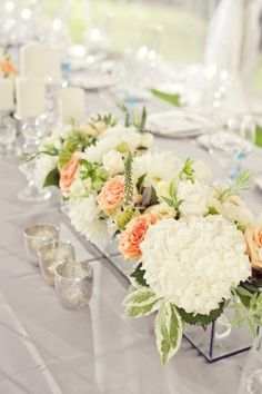 a vase filled with white flowers sitting on top of a table next to a lake