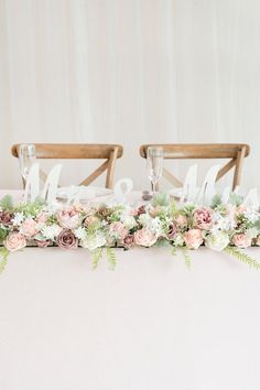 two wooden chairs with flowers and greenery on the back are sitting next to each other