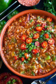 a bowl filled with beans and vegetables on top of a blue table next to tomatoes