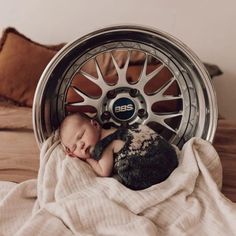 a baby sleeping on top of a blanket next to a tire