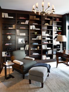 a living room filled with lots of bookshelves next to a desk and chair