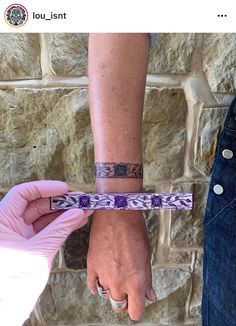 two people holding hands with wristbands on their wrists against a brick wall background