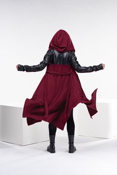 "This asymmetrical and modern cloak with a hood has two side pockets, a super comfy hood, and thumbholes for a fabulous look. Faux leather elements on the sleeves and the back and long belt as closure. The model in the picture is 176cm. ⅼ 5.8 ft. tall and is wearing size S / color: Burgundy 🌟 INFO: * Worldwide EXPRESS shipping - please provide a phone number for shipping documents * US Sizing XS to 4XL - size chart available below - all measurements of the body * We offer customization to Perso Queen Of The Kings, Gothic Cloak, Wizard Outfit, Gothic Cape, Wizard Cloak, Red Wizard, Cyberpunk Hoodie, The Runaway Bride, Steampunk Witch