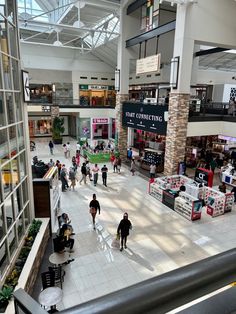 people are walking around in an indoor shopping mall with high ceilings and glass windows on the second floor