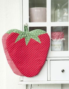 a red strawberry sitting on top of a white cabinet