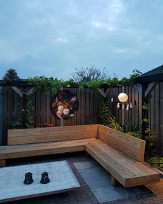 a wooden bench sitting on top of a patio next to a fire pit in the middle of a yard