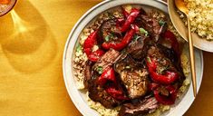 a white bowl filled with meat and red peppers next to a plate of couscous