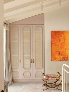 a white crib in the corner of a room with an orange painting on the wall