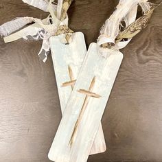 two wooden crosses are adorned with ribbons and burlaps on a table top