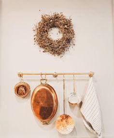 pots and pans are hanging on the wall next to a towel rack with a wreath