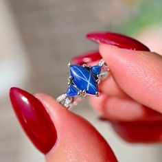 a woman's hand holding a ring with blue stones