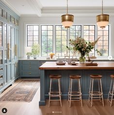 a large kitchen with blue cabinets and wooden flooring, along with two bar stools