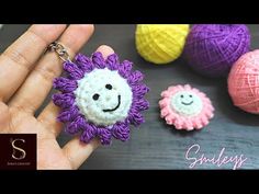 crochet keychain made to look like a flower with smiling faces on it