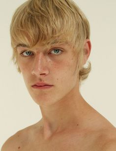 a young man with blonde hair and blue eyes is looking at the camera while wearing no shirt