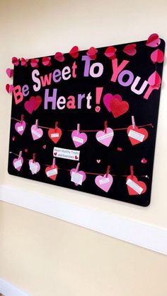 a sign that says be sweet to your heart hanging on a wall with hearts attached to it