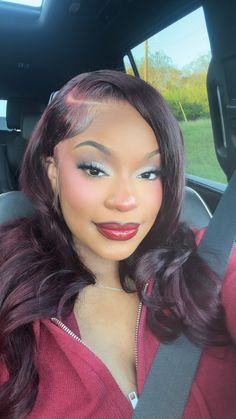 a woman sitting in the back seat of a car with long hair and red lipstick