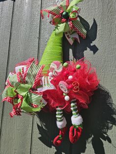 two christmas wreaths hanging on the side of a wooden fence with green and red ribbons