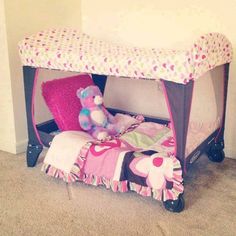 a teddy bear is sitting on a bed with a pink and green canopy over it