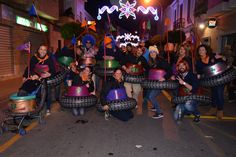 a group of people holding up large tires in the middle of a street at night