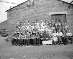 an old black and white photo of men in front of a brick building