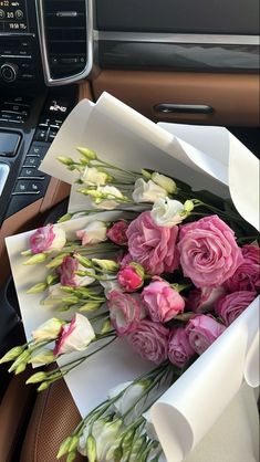 a bunch of flowers sitting inside of a box on the dash board of a car