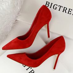 a pair of red high heeled shoes sitting on top of a white box next to a pillow