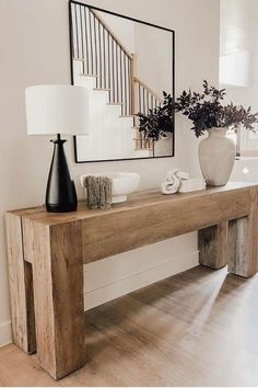 a wooden table with two vases on top of it next to a stair case