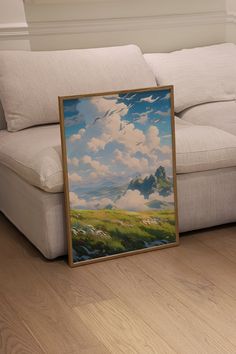 a painting sitting on top of a wooden floor next to a white couch in a living room