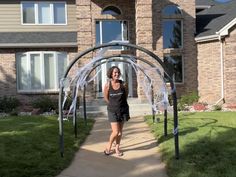 a woman is walking down the sidewalk in front of a house with a large arch