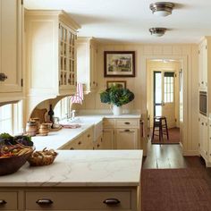 a kitchen with white cabinets and an island in the middle is decorated with fruit, vegetables and other items