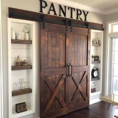 an open barn door with the word pantry written on it and shelves behind it, in front of a window