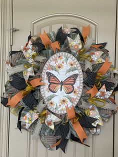 a wreath with a butterfly on it is hanging on the front door and decorated with orange ribbons