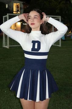 a woman in a cheerleader uniform posing for a photo with her hands on her head